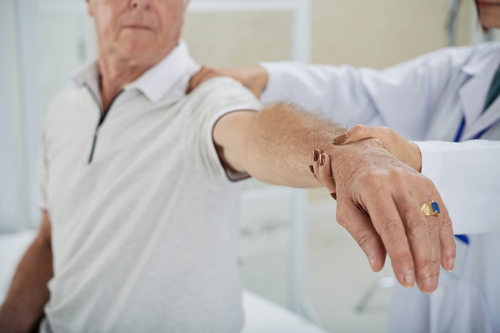 Cropped image of doctor examining patients arm after rehabilitation