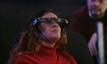 Una espectadora usando gafas de entretenimiento accesible, con la que se pueden personalizar subtítulos