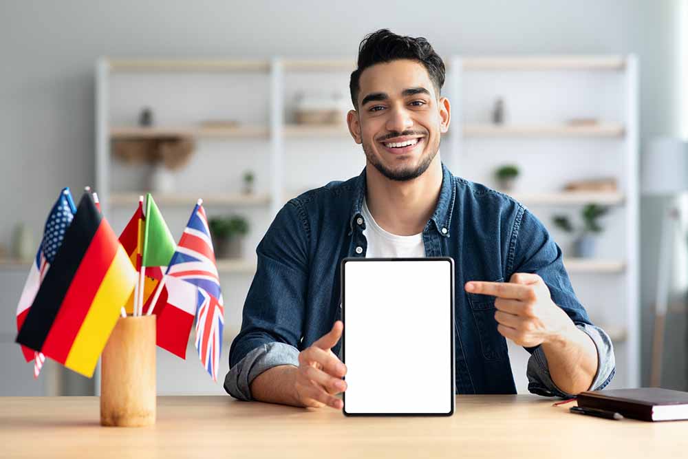 Cheerful arab guy pointing at digital tablet with empty screen